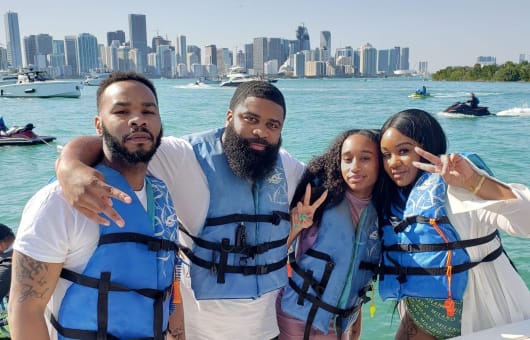 Group of friends wearing life jackets posing in front of the Miami skyline.