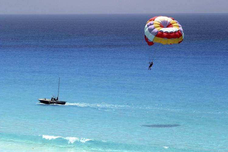 A person parasailing behind a boat on bright blue waters